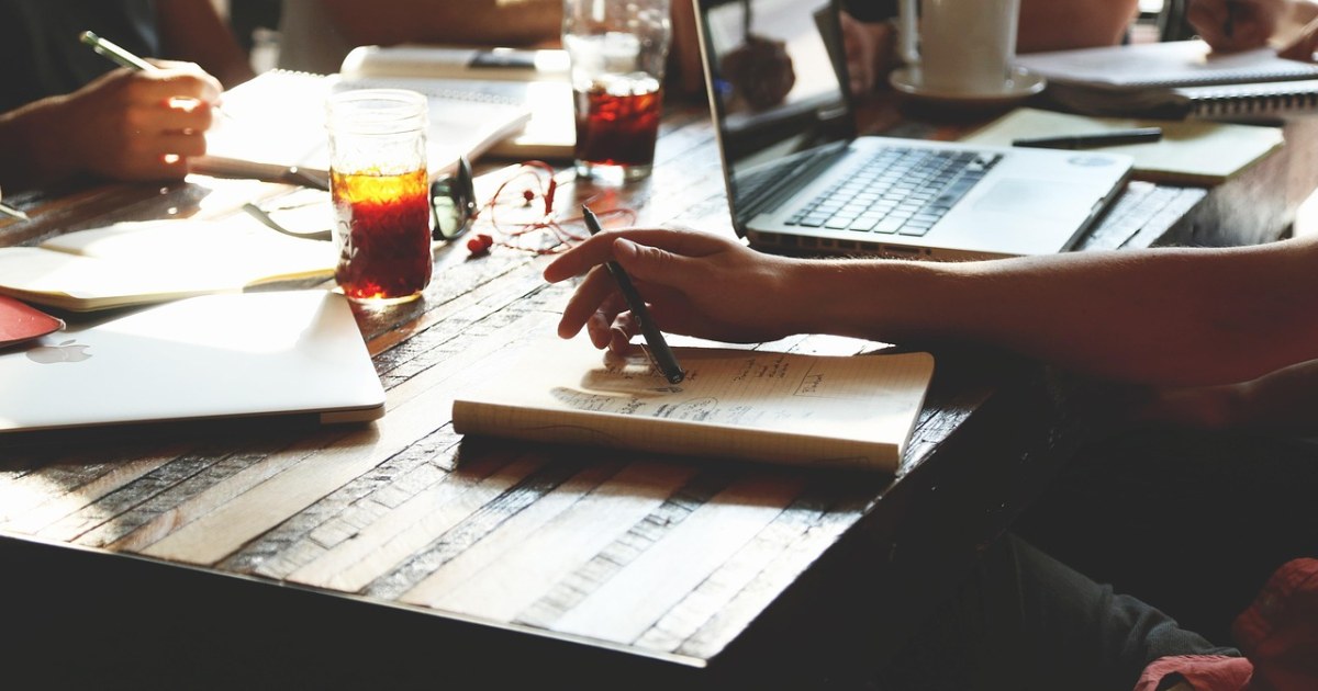 Laptop and notebook for an AI note-taking app comparison.
