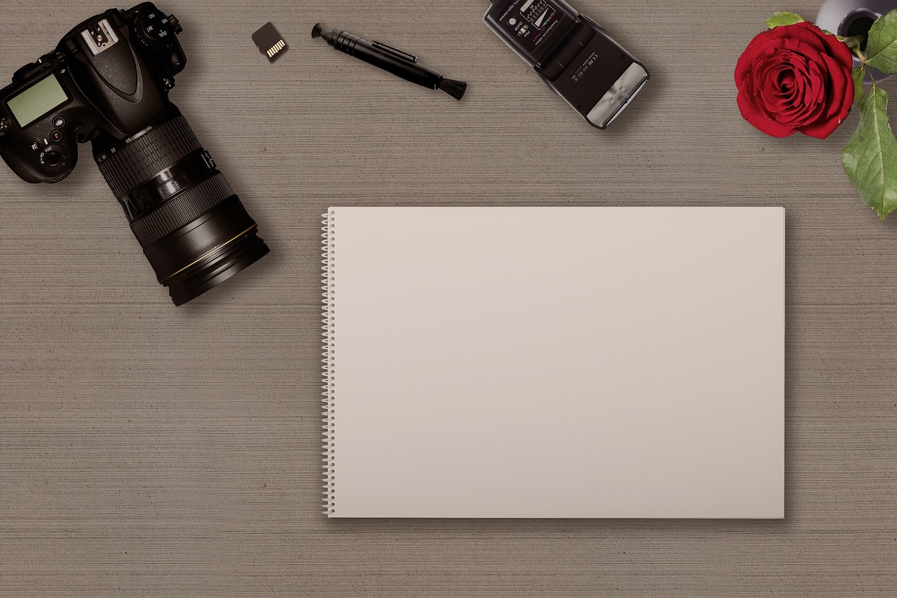 Digital camera, notebook and memory card representing travel photo backup planning.